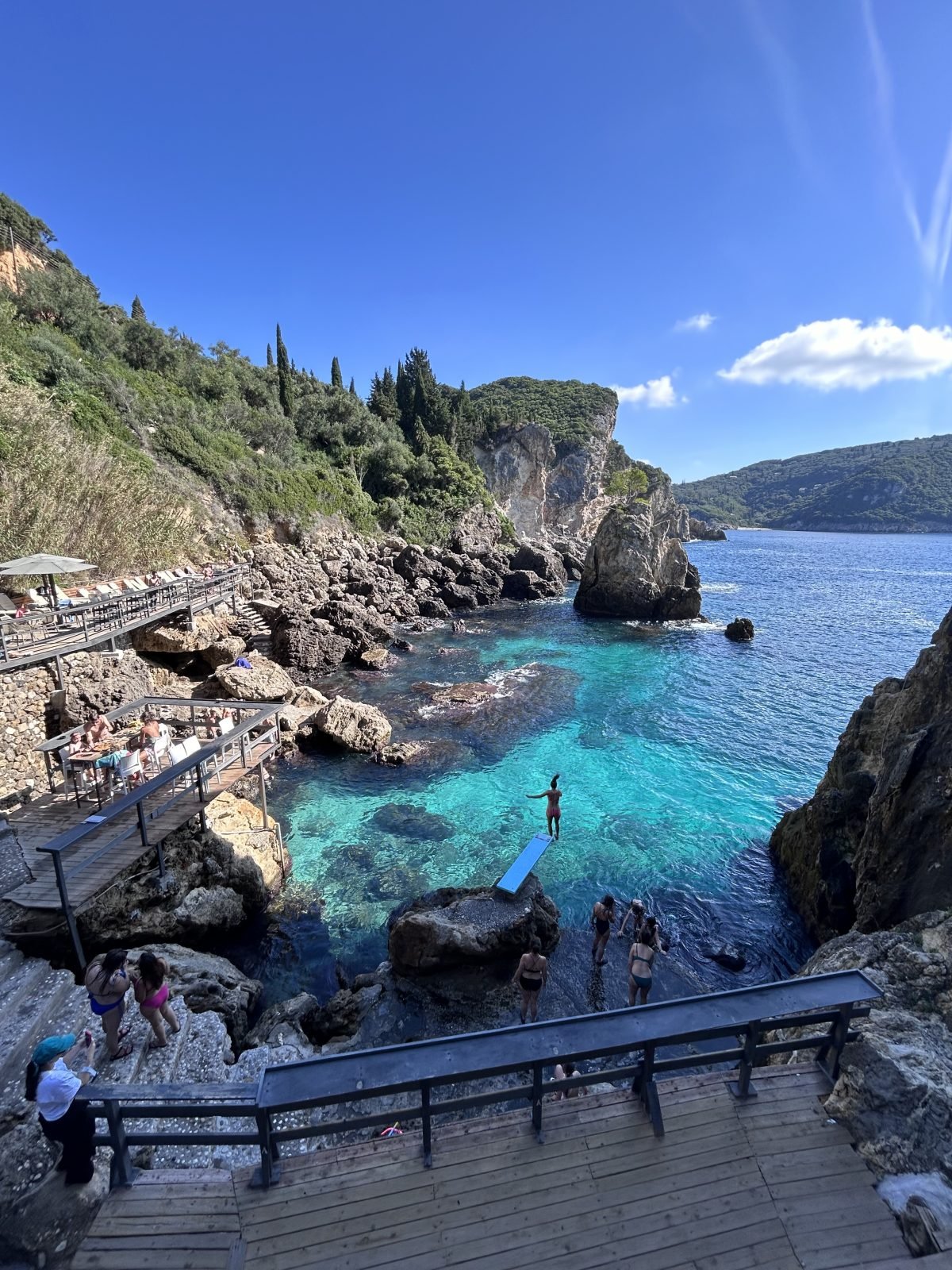 Družine uživajo na skrivni plaži s kristalno modrim morjem na otoku Korfu, Grčija.