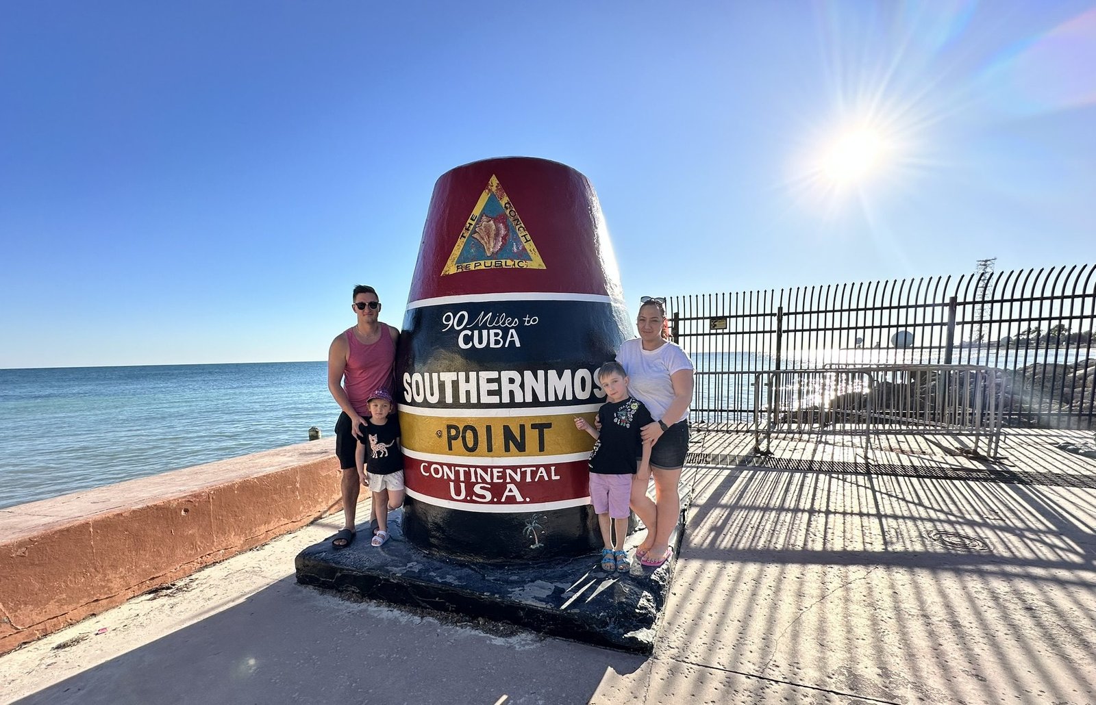 Družina stoji pred znamenitim Southernmost Point v Key Westu, najjužnejši točki celine ZDA.