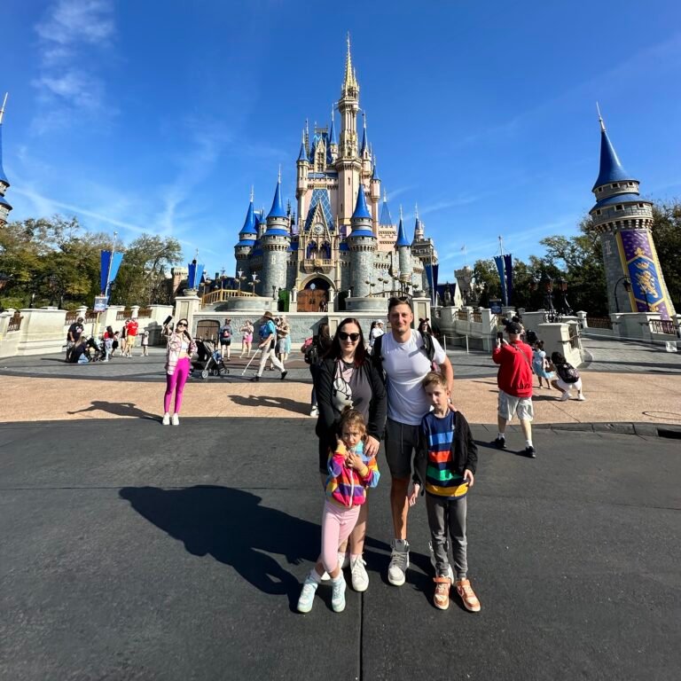 Family of four visiting Magic Kingdom with kids in front of Cinderella Castle