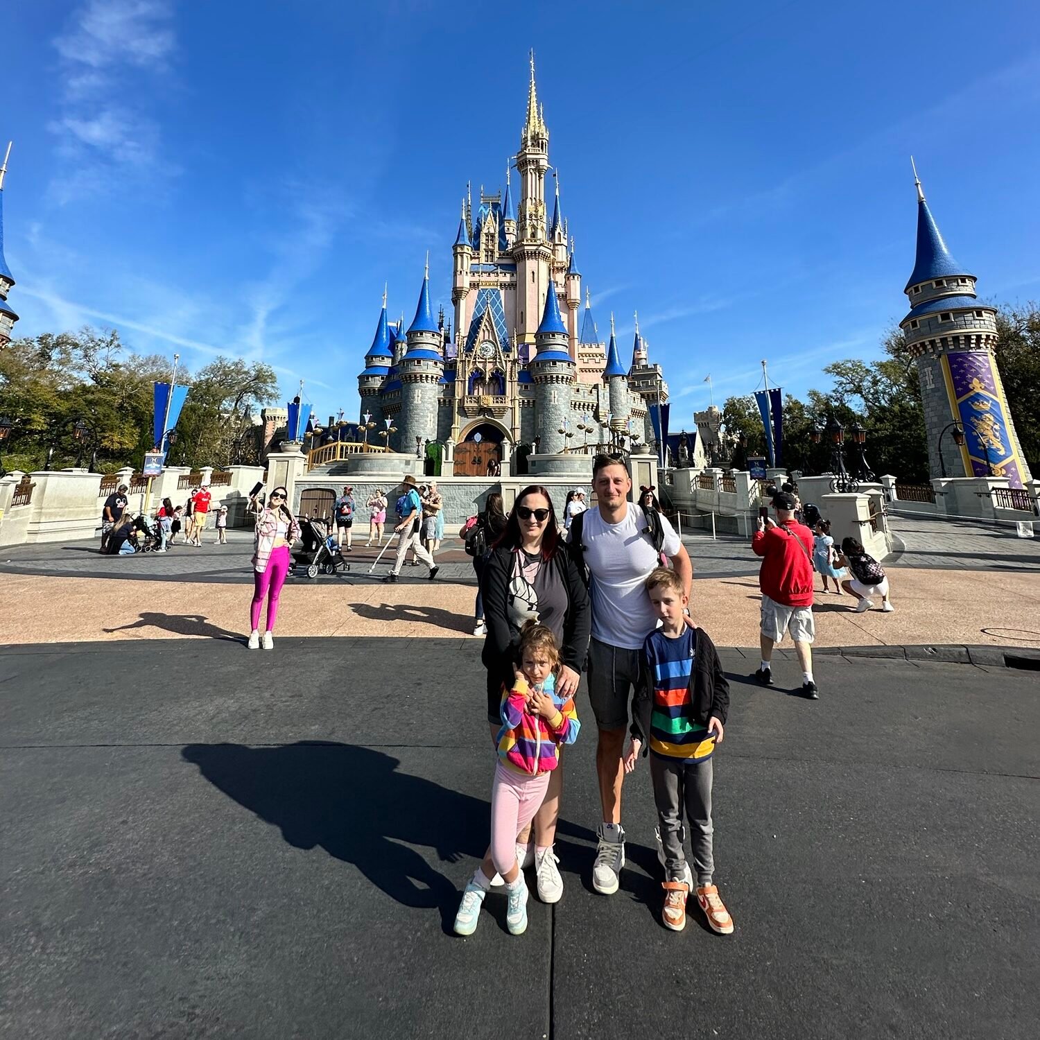 Family of four visiting Magic Kingdom with kids in front of Cinderella Castle