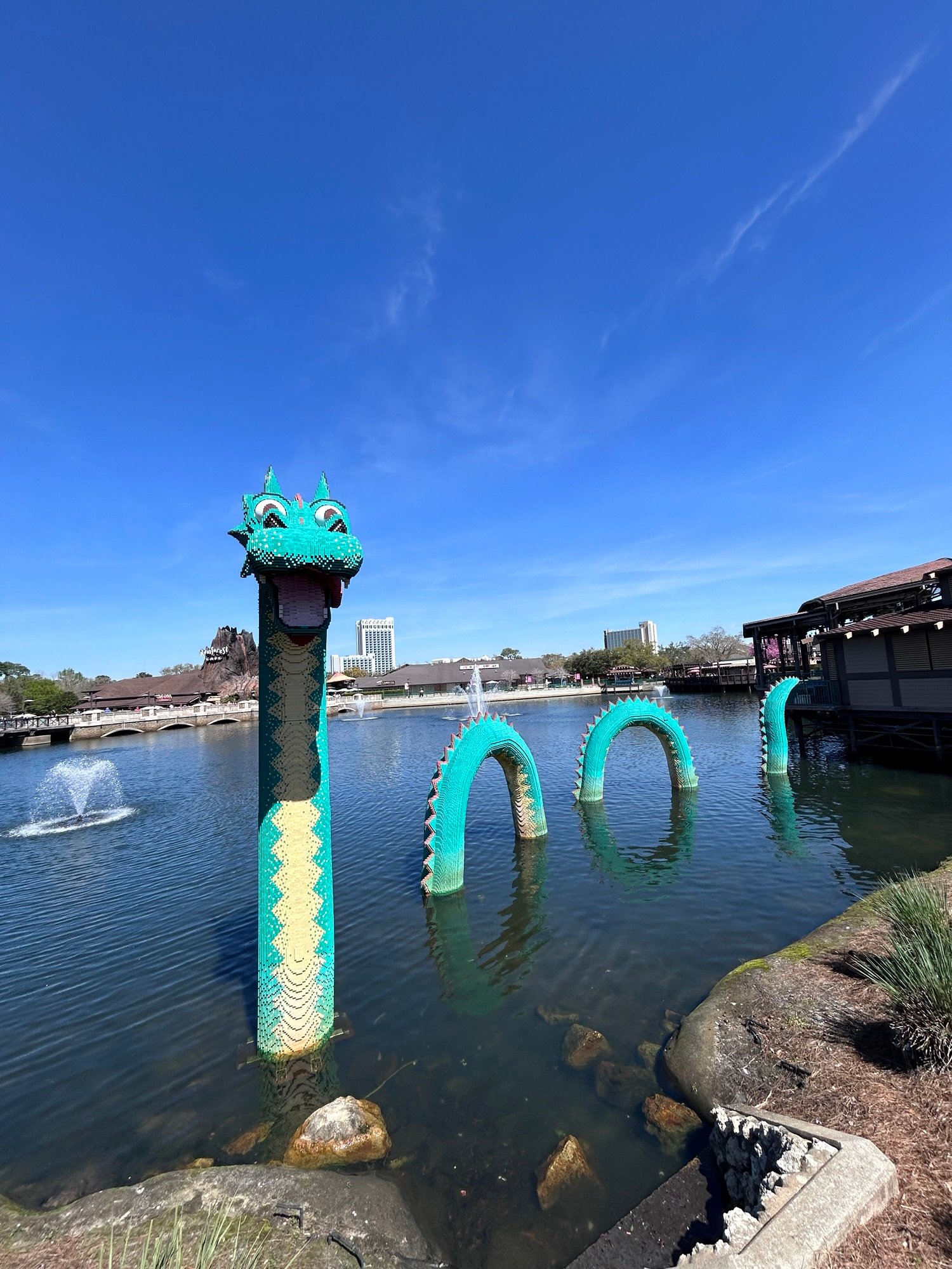 Giant green LEGO dragon emerging from the water at Disney Springs