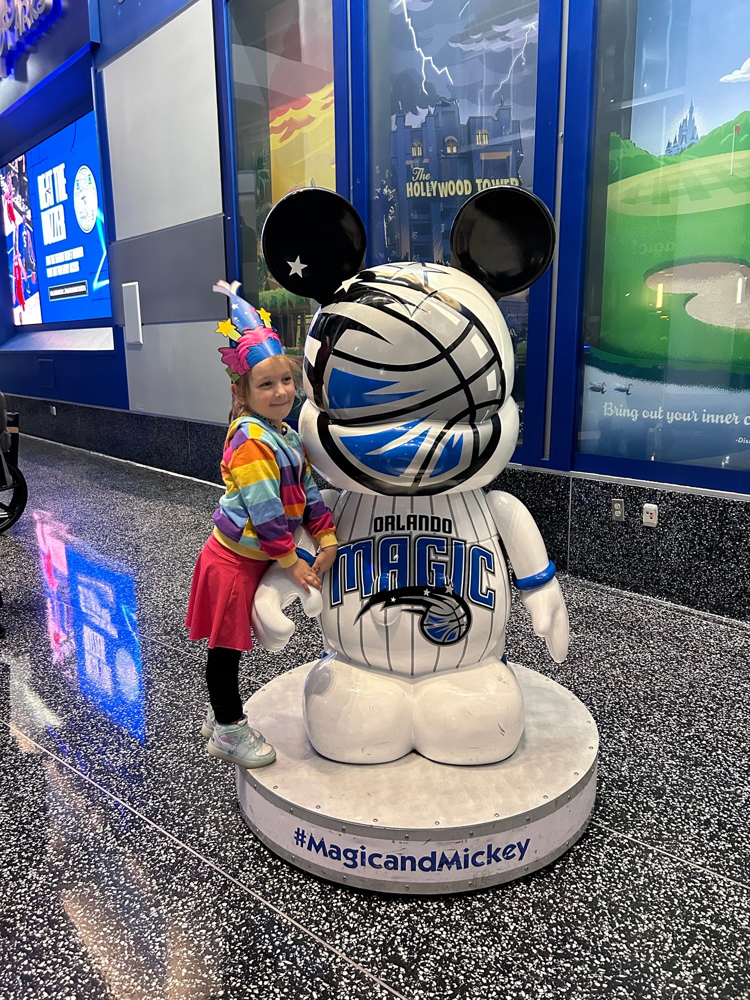 Child posing beside Orlando Magic Mickey Mouse basketball statue at Kia Center