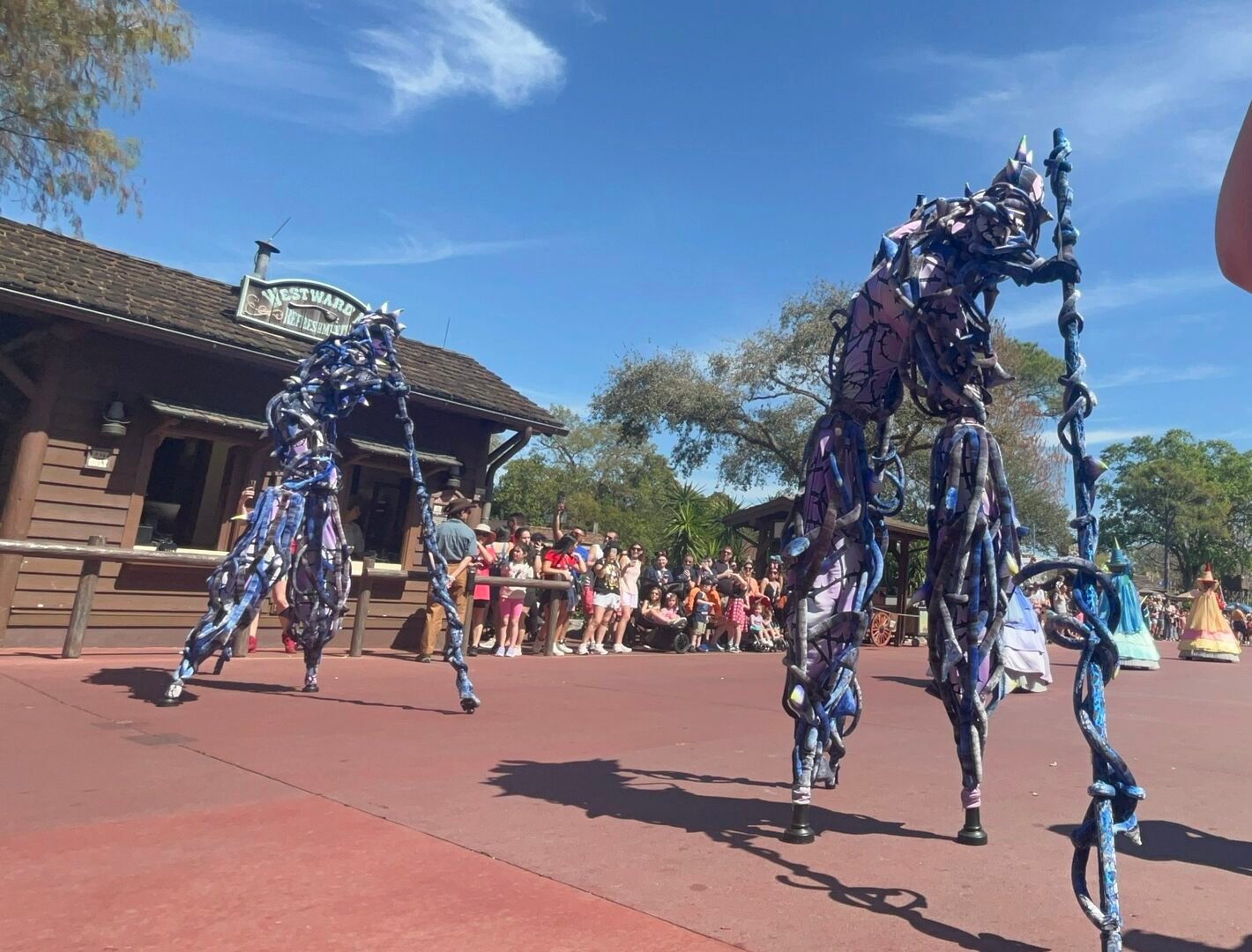 Colourful stilt-walking performer entertaining visitors during a Magic Kingdom parade