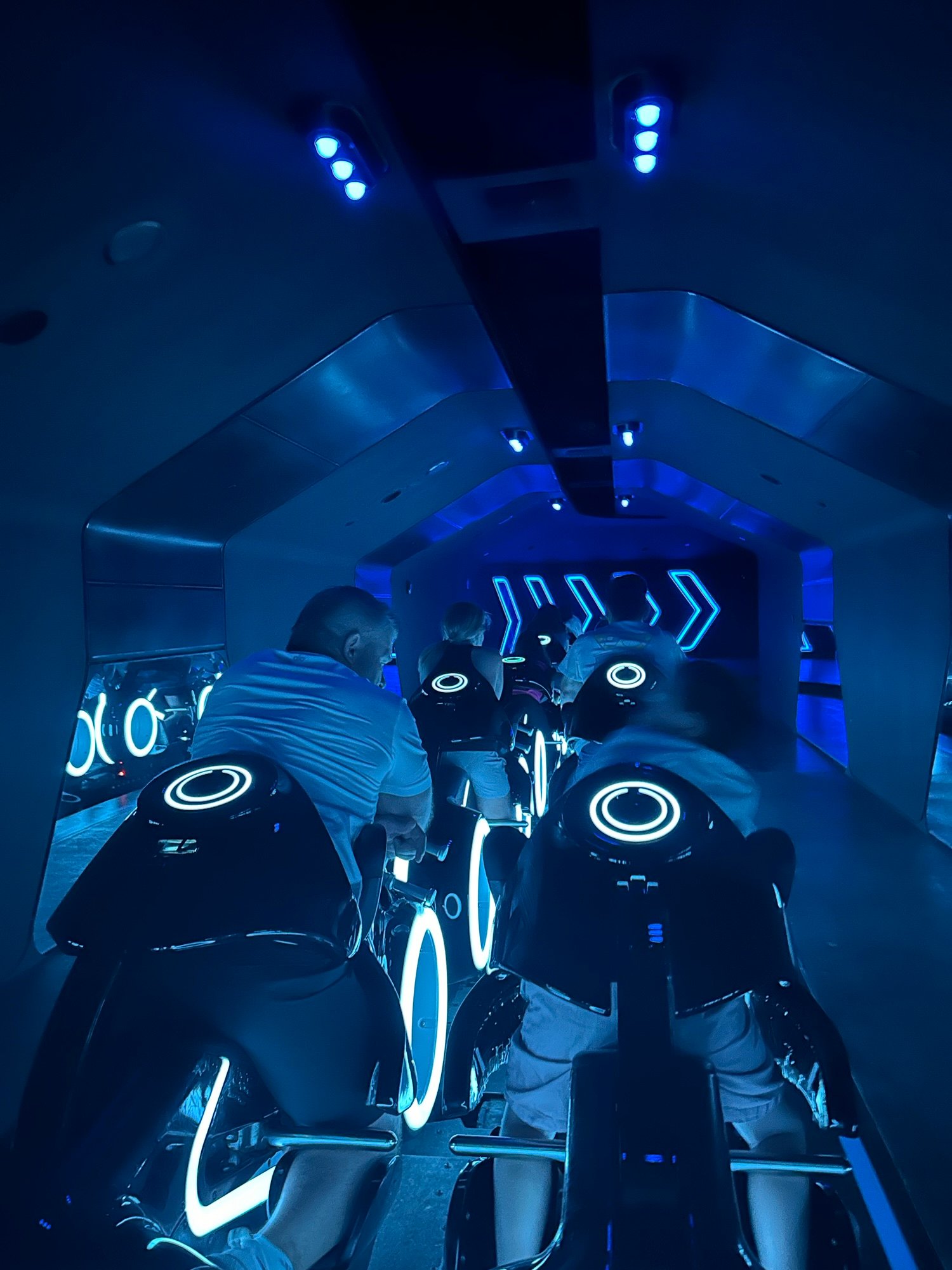 Riders on TRON Lightcycle Run inside the futuristic blue-lit launch area at Magic Kingdom